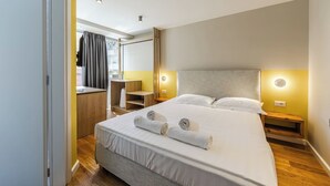 A hotel room with a large bed, bedside tables, a desk, and a wardrobe. - Yellow Studio 106 | Love in Colours Collection by PikHost (Durrës)