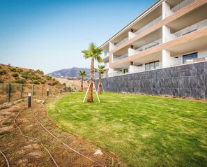 A modern building with a flat roof, multiple balconies, and a well-maintained lawn with palm trees. - Sole Mio - Sea View - Terrace - Pool (Fuengirola)