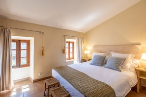 A bedroom with a large bed, two bedside tables, a window with curtains, and a hanging lamp. - Cosy Townhouse with views (Pollensa / Pollença)