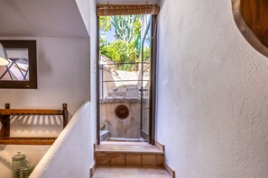 A narrow staircase leading to an outdoor area with a glass door, a wooden shelf, and a metal railing. - Cosy Townhouse with views (Pollensa / Pollença)
