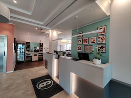 A reception area with a counter, a refrigerator, and a wall decorated with framed pictures.