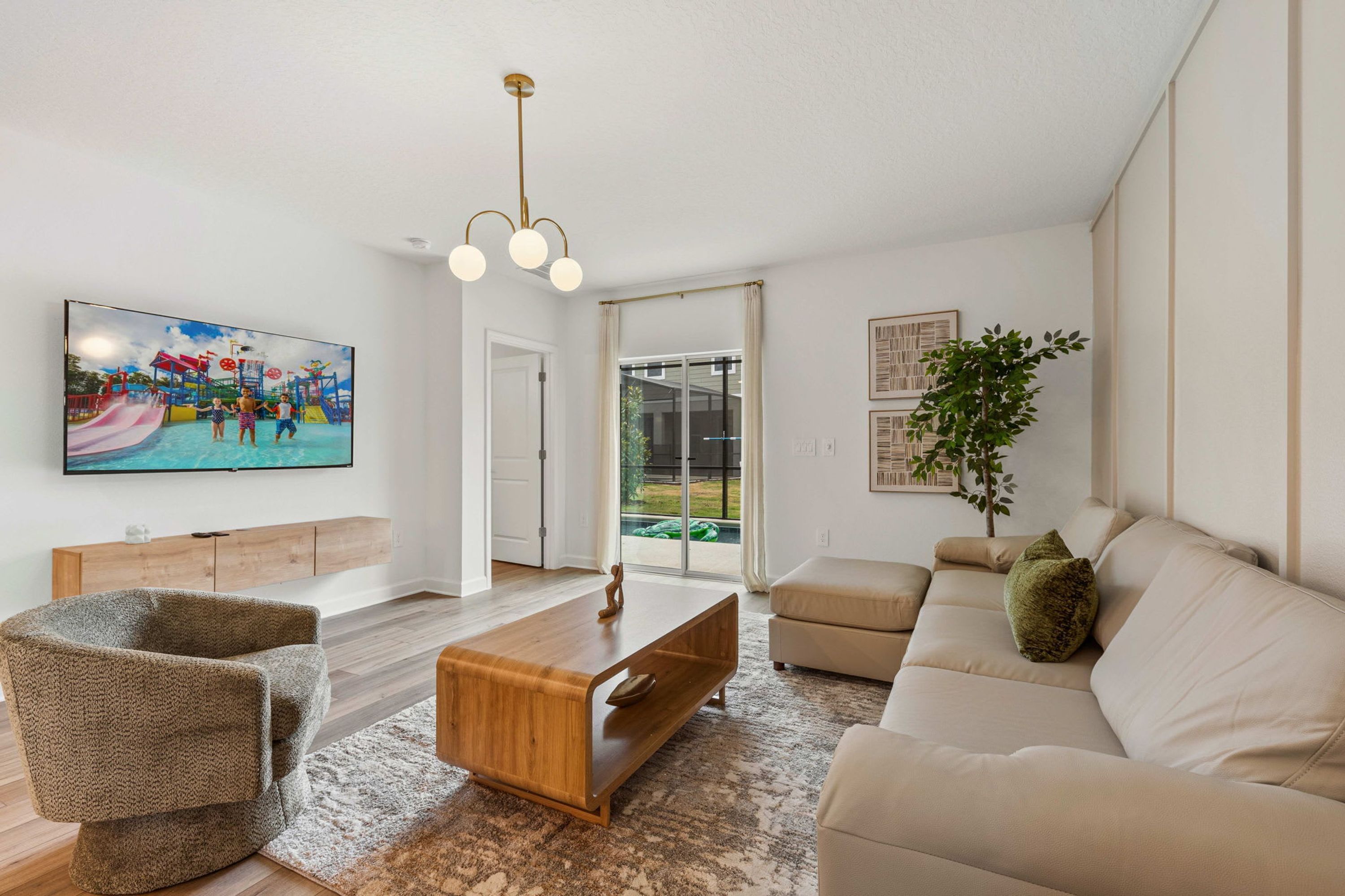 Ein Wohnzimmer mit Fernseher, Sofa, Sessel, Couchtisch und einer Pflanze.