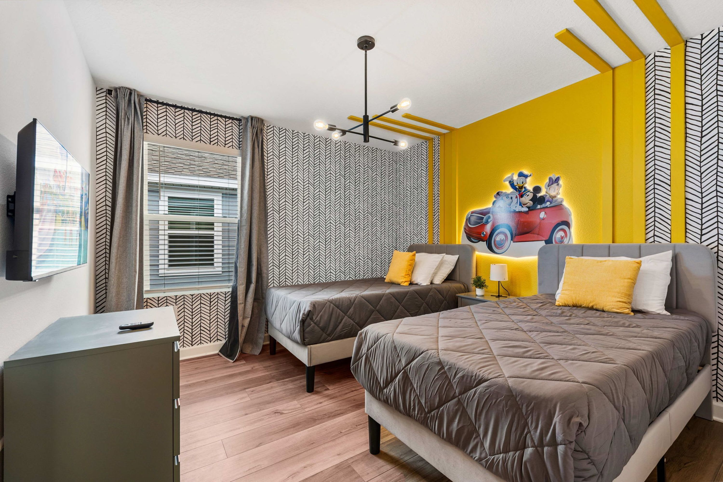 Une chambre d’hôtel avec deux lits, une télévision, un bureau et une fresque murale.