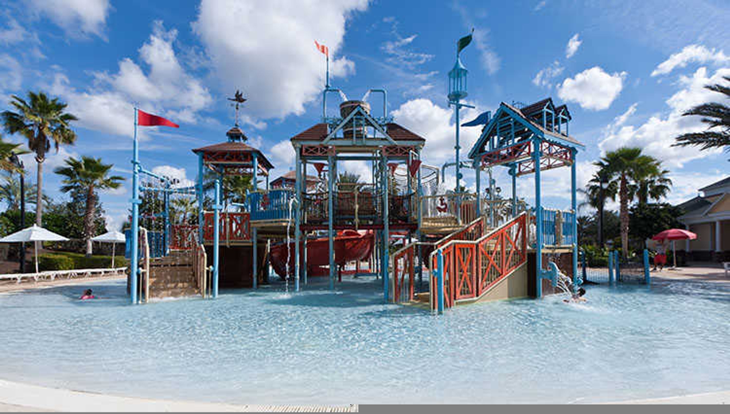 Un parque acuático con una estructura de juegos central, varias toboganes y una zona de piscina.