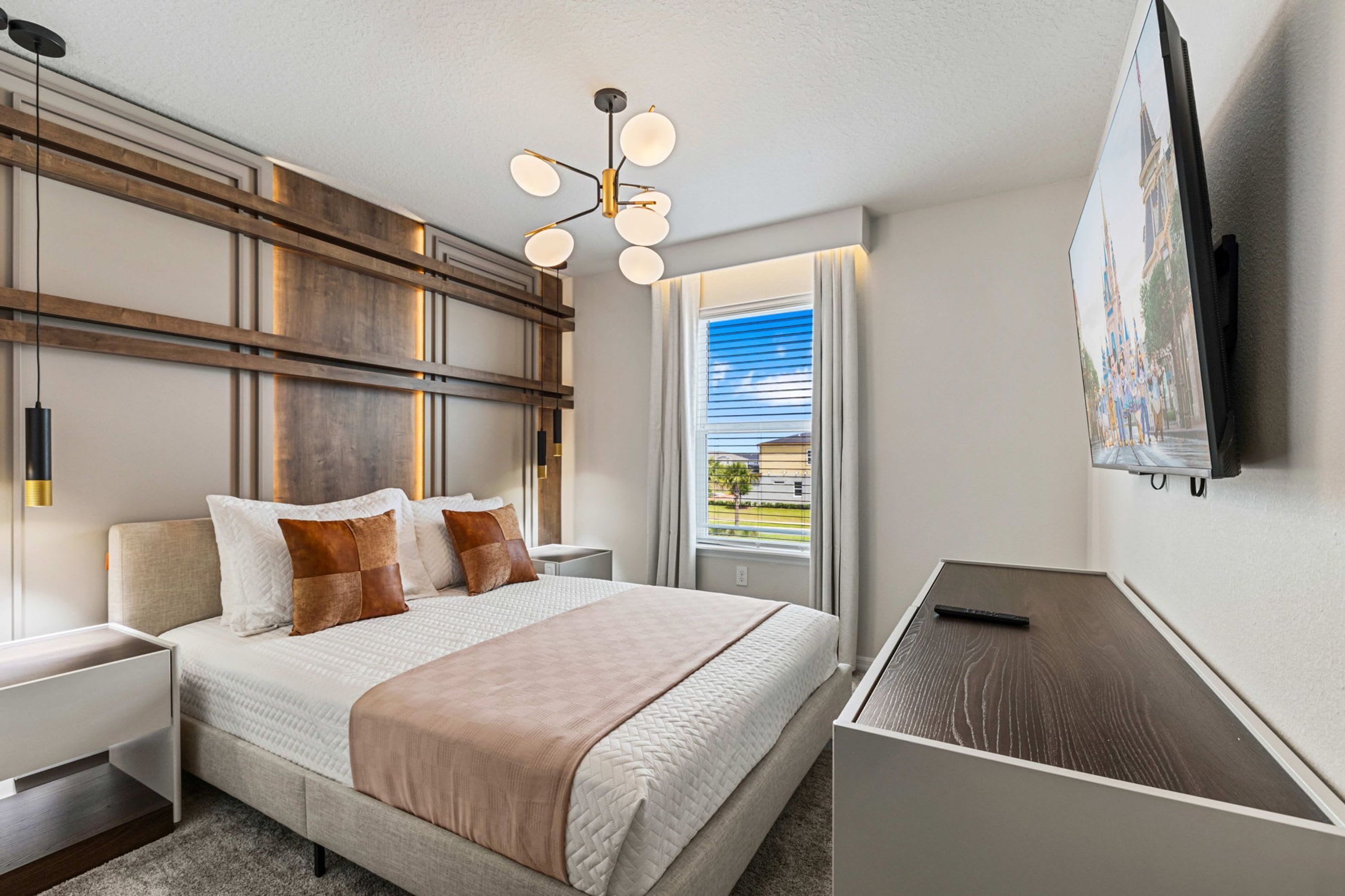 A hotel room with a bed, bedside tables, a desk, a flat-screen TV, and a window with a view.