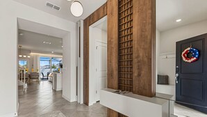 Ein modernes Interieur mit einer Holzwand, einem Glastisch und einer dunklen Tür mit einem Kranz.