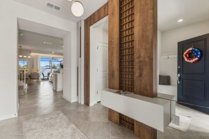 Ein modernes Interieur mit einer Holzwand, einem Glastisch und einer dunklen Tür mit einem Kranz.
