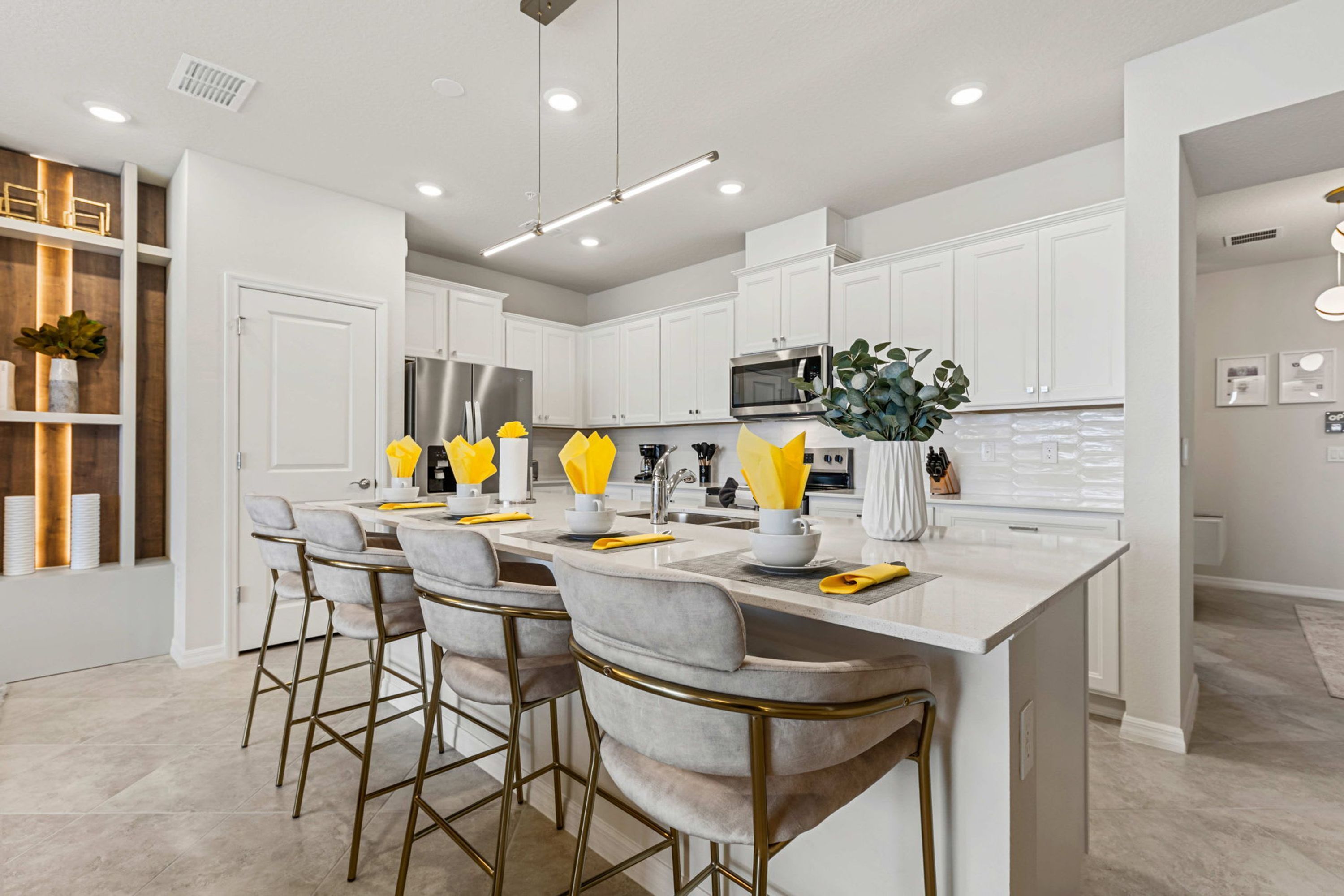 A modern kitchen with white cabinets, stainless steel appliances, and a central island with bar stools.
