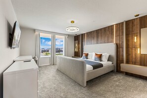 Ein modernes Hotelzimmer mit Bett, Schreibtisch, Fernseher und einem großen Fenster mit Blick auf die Stadt.