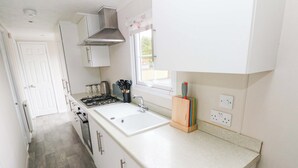 Une cuisine dotée d’un plan de travail blanc, d’une cuisinière en acier inoxydable et d’une fenêtre offrant une belle vue.