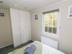 A bedroom with a bed, a window with a view, a radiator, and a wardrobe.