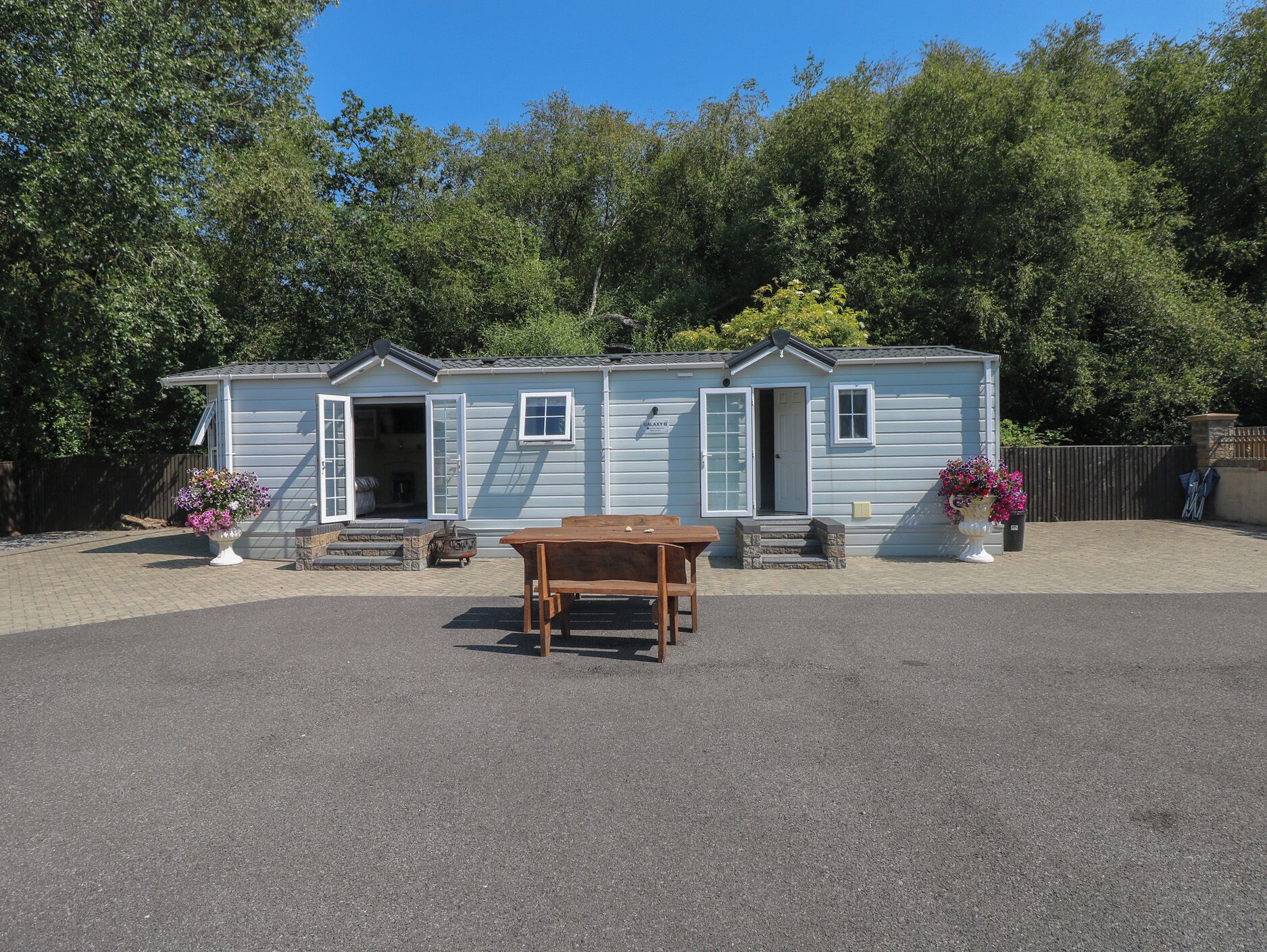 A small, single-story mobile home with a front porch and a table.