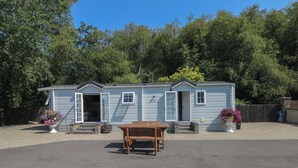 Une petite maison mobile de plain-pied, dotée d’un porche à l’avant et d’une table.