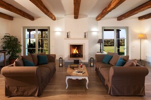 A living room with two sofas, a fireplace, and large windows. - Podere La Sassicaia – Villa with Private Pool in the Tuscan Hills (Manciano)