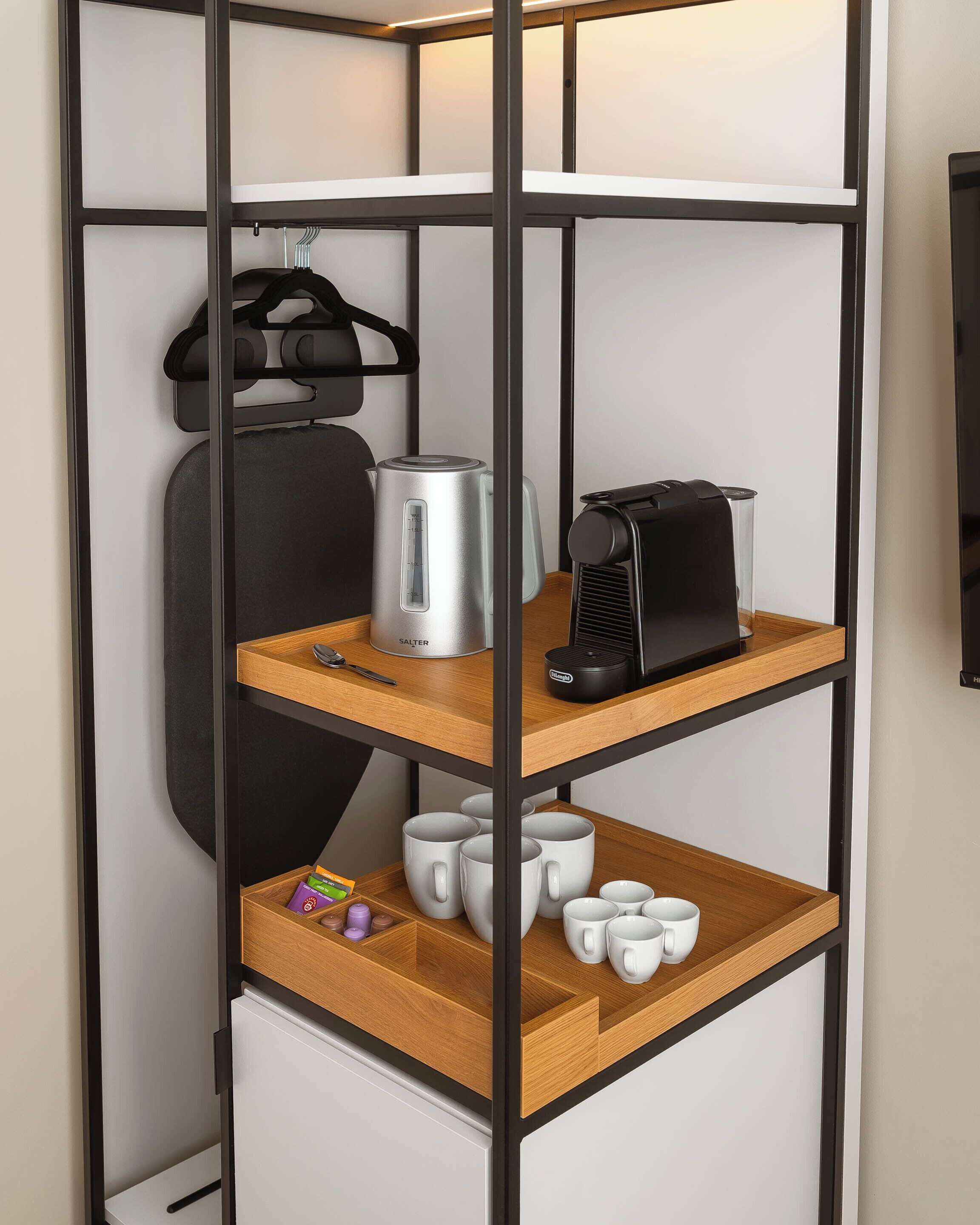 A modern, multi-tiered storage unit with a kettle, a coffee maker, and mugs.