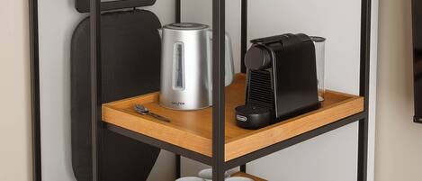 A modern, multi-tiered storage unit with a kettle, a coffee maker, and mugs.