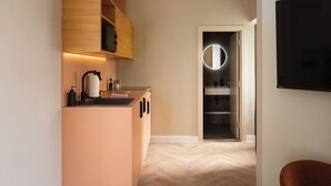 Une cuisine moderne équipée d’un four à micro-ondes encastré, d’un évier et d’un plan de travail sur lequel se trouvent une bouilloire et un distributeur de savon.