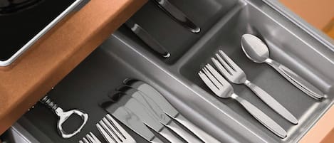 A kitchen drawer with utensils and a kettle.