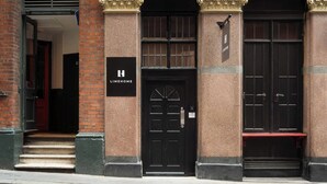 Un immeuble avec une porte noire, une enseigne indiquant « LIMEHOME » et un banc à l’extérieur.