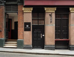 A building with a black door, a sign reading 'LIMEHOME,' and a bench outside. - Limehome London St. Paul's (London)
