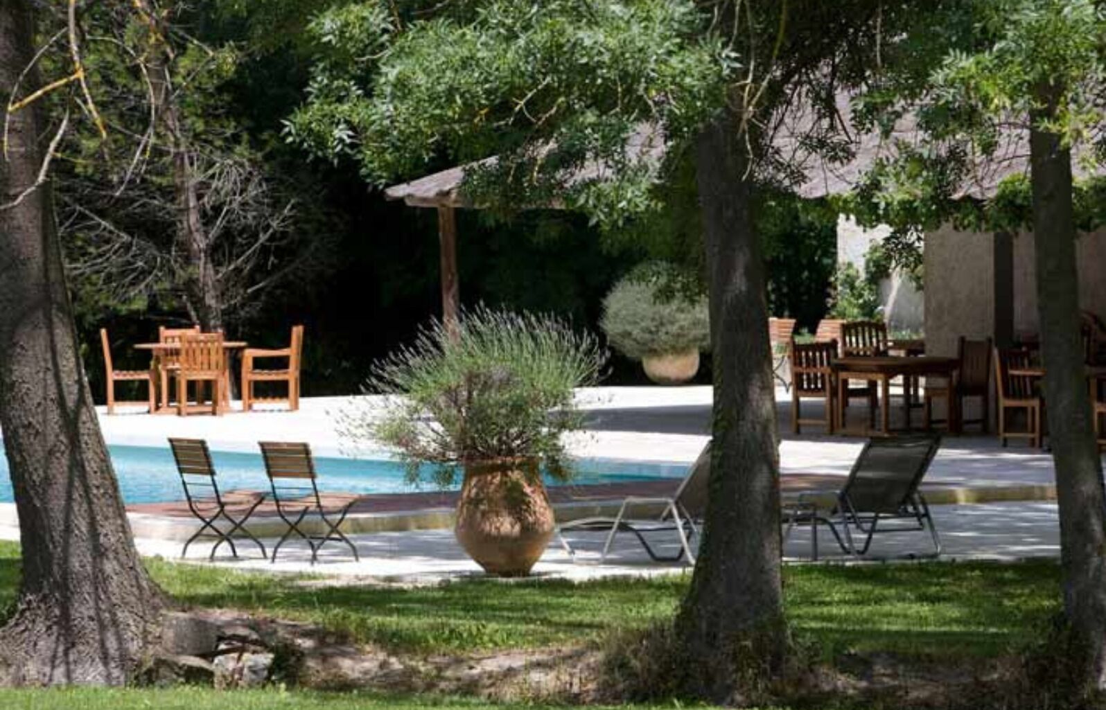 An outdoor pool area with lounge chairs and wooden tables.