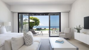 A modern hotel room with a bed, a sofa, a coffee table, and a TV. - Casa del Muelle in Punta Mita (Punta de Mita)