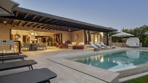 A modern outdoor pool area with lounge chairs, a covered seating area, and a patio with a pergola. - Casa del Muelle in Punta Mita (Punta de Mita)