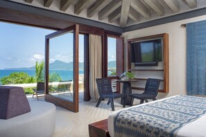 Habitación de hotel con balcón, cama, televisor y zona de comedor.