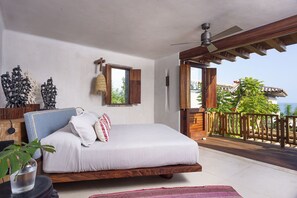 Un dormitorio con cama, ventana, ventilador de techo y balcón con barandilla.