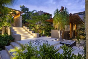 Un espacio exterior moderno con una escalera de piedra, palmeras y un diseño circular decorativo en el suelo.