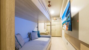 Moderni hotellihuone, jossa on sänky, työpöytä ja seinälle asennettu televisio.