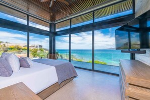 A bedroom with a large bed, a wooden desk, and a TV. It has large windows with a view of the ocean. - Kupuri 32 In Kupuri Punta Mita (Punta de Mita)