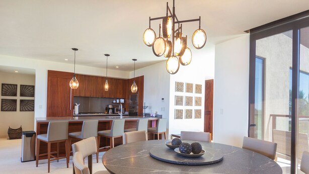 A modern kitchen with a central island, pendant lighting, and a dining area with a round table and chairs. - Condo Ara in Punta Mita (Punta de Mita)