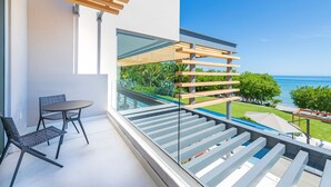 A modern balcony with a glass railing, a dining table, and chairs, overlooking a pool and ocean view. - Casa Brisa in Punta Mita (Punta de Mita)