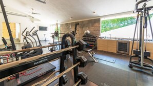 A gym with exercise equipment, a stone wall, and a view of greenery. - Casa Brisa in Punta Mita (Punta de Mita)