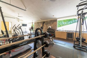 A gym with exercise equipment, a stone wall, and a view of greenery. - Casa Brisa in Punta Mita (Punta de Mita)
