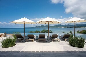 A poolside area with lounge chairs and umbrellas, overlooking a body of water and distant mountains. - Casa Milagro Diario - Mita Residential Punta Mita (Punta de Mita)