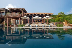 A resort with a pool, lounge chairs, umbrellas, and a reflection in the water. - Casa Milagro Diario - Mita Residential Punta Mita (Punta de Mita)