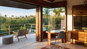 Un espacio exterior moderno con puerta de vidrio que da a un balcón, una mesa de comedor con sillas y un mueble empotrado para entretenimiento.