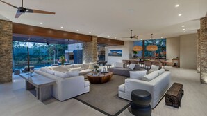 Un espacio habitable amplio con diseño moderno, que incluye un sofá grande, una mesa de centro y una zona de comedor con vistas al exterior.