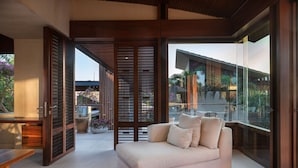 Una sala de estar moderna con un sofá, un separador de vidrio y vistas al exterior.