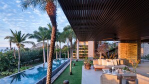 Un espacio al aire libre moderno con piscina, mobiliario y plantas tropicales.