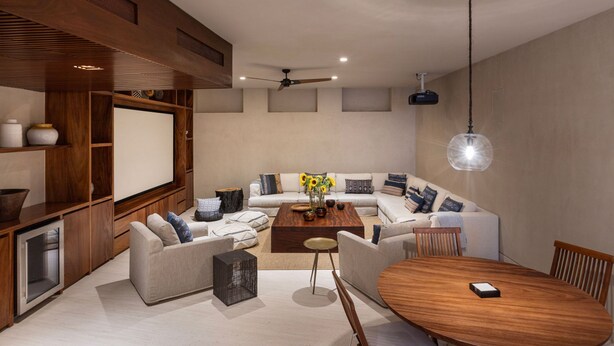 Una sala de estar moderna con un sofá seccional, una mesa de centro, una mesa de comedor y estanterías empotradas de madera.