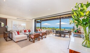 A spacious living area with a sofa, chairs, and a dining table. A large window offers a view of the ocean. - Condo Piscis in Punta Mita (Punta de Mita)
