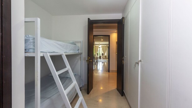 Un pasillo estrecho que conduce a una habitación con una litera y una escalera.