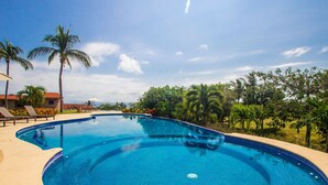 Piscina azul cristalina rodeada de palmeras y un cielo despejado.