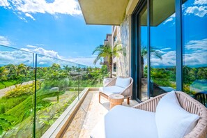 A balcony with wicker furniture, a glass railing, and a view of greenery. - Condo Ensue o in Punta Mita (Punta de Mita)