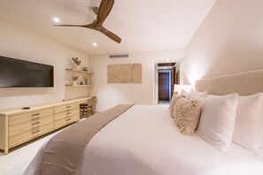 A bedroom with a bed, a wooden dresser, a flat-screen TV, a ceiling fan, and a door leading to another room. - Condo Ensue o in Punta Mita (Punta de Mita)