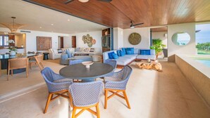 A spacious living area with a round table, blue patterned chairs, a sofa with blue cushions, and a ceiling fan. - Condo Las Olas in Punta Mita (Punta de Mita)