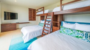 A bedroom with bunk beds, a TV, a wooden cabinet, and a blue rug. - Condo Las Olas in Punta Mita (Punta de Mita)